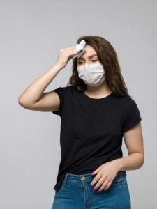Wanita muda menggunakan masker medis dan T-Shirt warna hitam